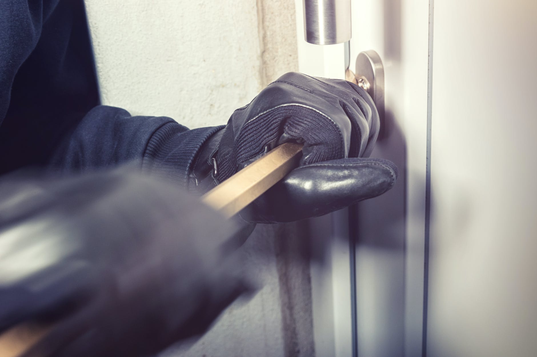 person opening a door with a crowbar
