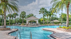 Relaxing tropical poolside scene with palm trees, gazebo, and clear blue water at a luxury resort.