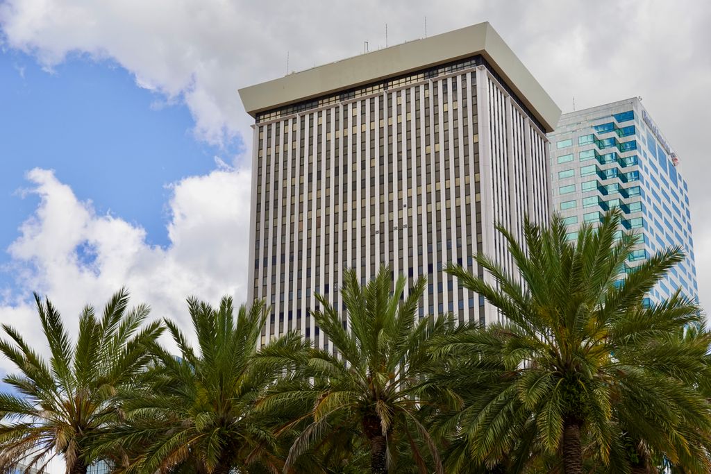 Tall skyscraper in Tampa with palm trees against a cloudy sky.