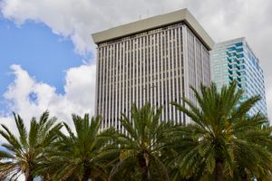 Tall skyscraper in Tampa with palm trees against a cloudy sky.