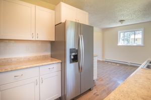 Bright modern kitchen featuring stainless steel appliances and wooden flooring.